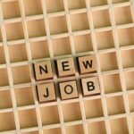 Discover the excitement of a new job with wooden letter tiles spelling 'NEW JOB' on a grid.